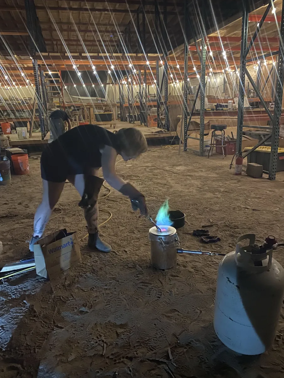 Blue flame rising from a small furnace on the workshop floor