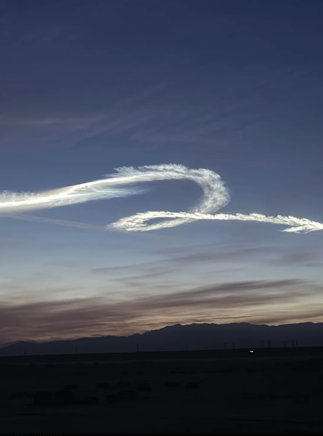 Rocket contrail swirl over the desert at dusk