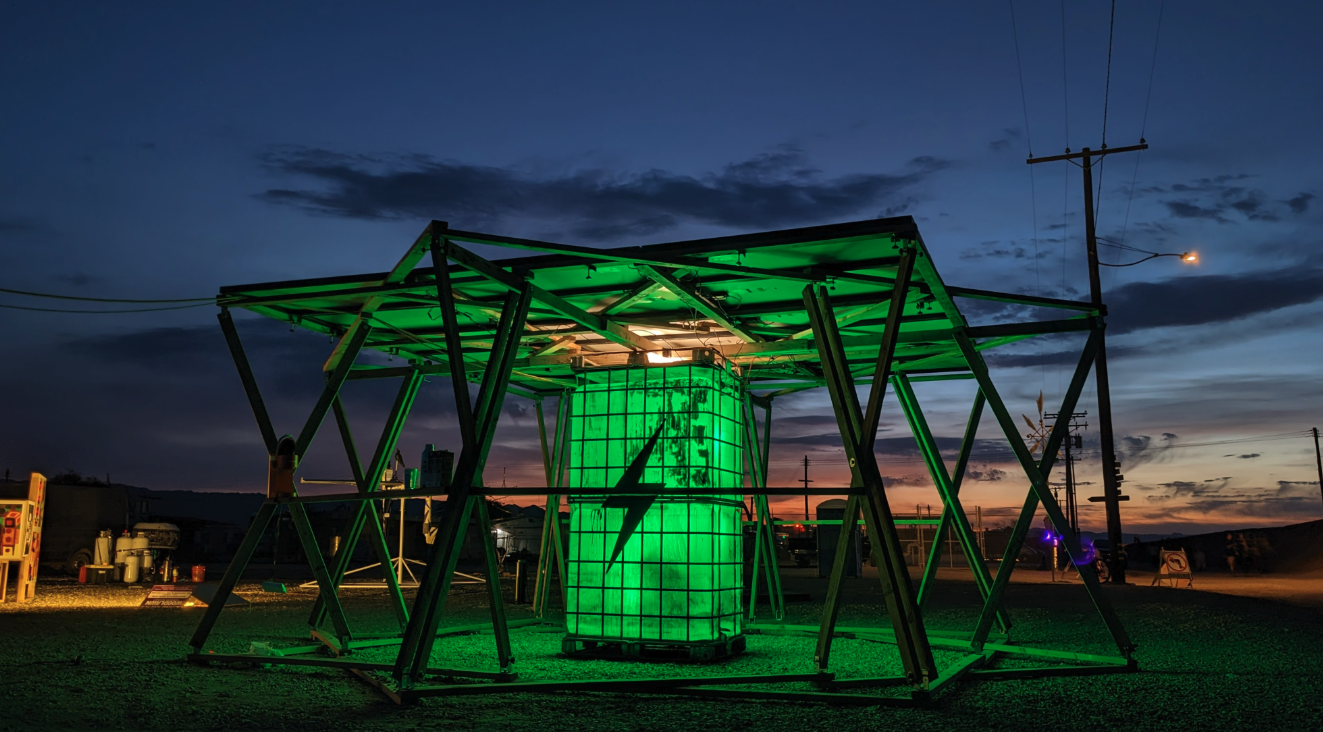 Green-lit folding solar canopy structure over an illuminated water tank at dusk
