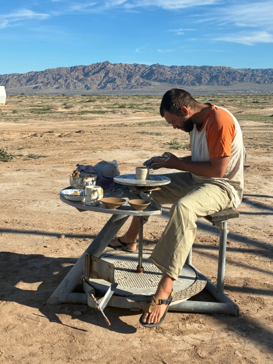 Throwing pottery on the wheel with mountains behind