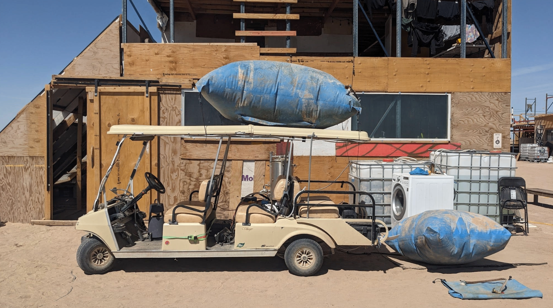 A modified golf cart parked in front of the camp workshop, carrying blue biogas bladders