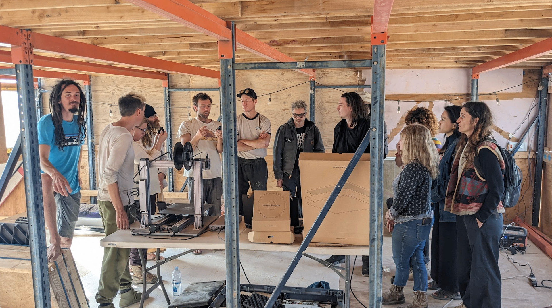 Group gathered around a 3D printer demo inside the Tool Camp workshop